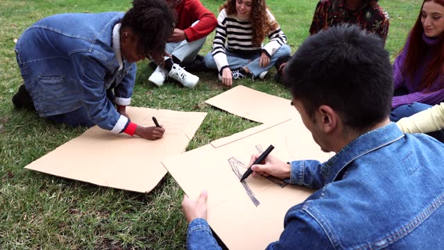 male and female activists preparing posters on social issues, no war, peace, no racism.