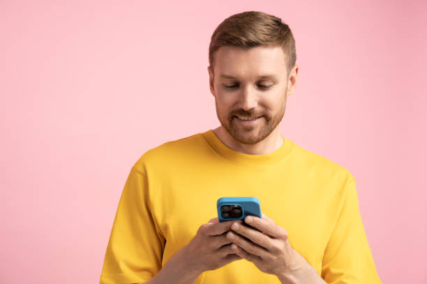 istock Man with phone, studio portrait. Guy uses smartphone, typing, texting, chatting in messengers online 1765677603
