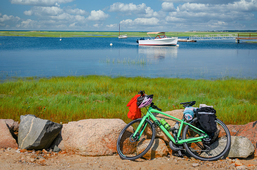 A green bicycle leans against a group of rocks at Mill Creek in Yarmouth, Massachusetts while its owner takes a quick swim.