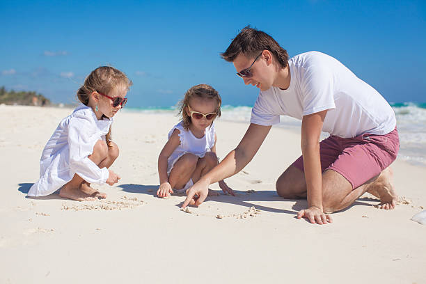 istock Happy father and his adorable little daughters playing on beach 176568560