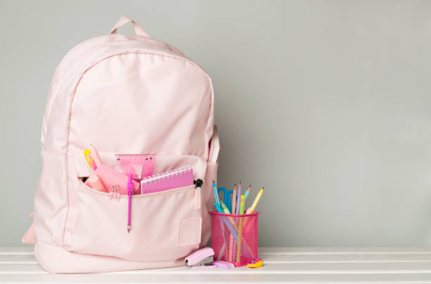 istock Pink school backpack with stationery on wooden table 1765692451