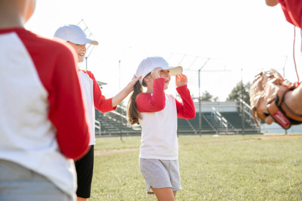 istock Two young girls in baseball attire engage in conversation, while another player and their coach observe the interaction 1765702253