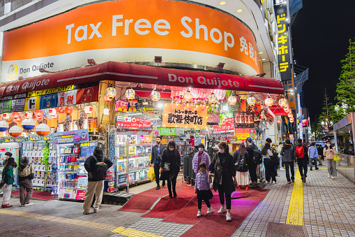Tokyo, Japan - April 11, 2023: tax free shop in the Kabukicho district with unidentified people at night. Kabukicho is a famous entertainment district in Shinjuku with many movie theaters hostess clubs and love hotels