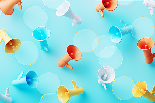 Colorful speech bubbles and megaphones on blue megaphones on blue background. Horizontal composition.