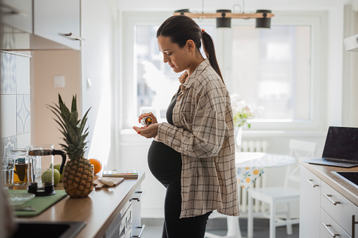 Pregnant woman using prenatal vitamin suplements during pregnancy