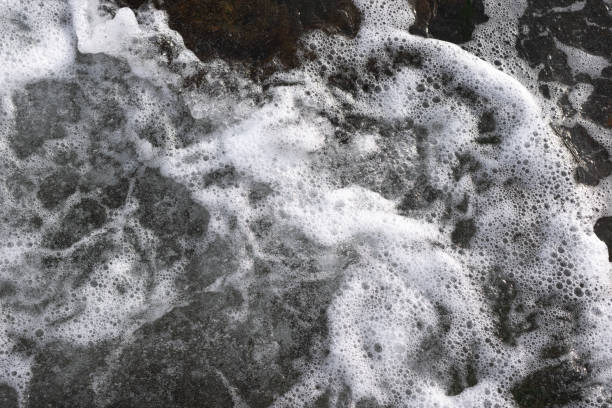 istock Sea water covering dark beach rocks. 1765775919
