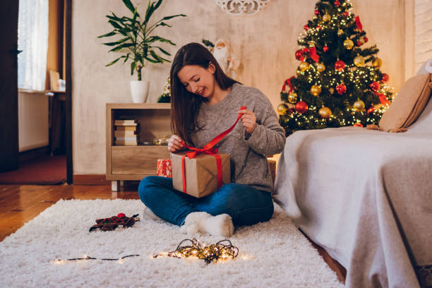 istock A young woman opens a Christmas present at home 1765782065