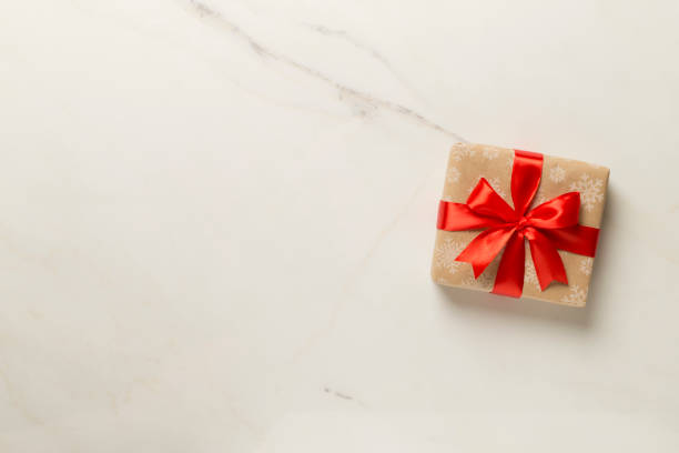 istock Gift box with red ribbon bow on marble background, top view 1765839608