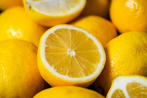 Composition of whole and half ripe, yellow lemons. Lemon wallpaper, close up, full frame