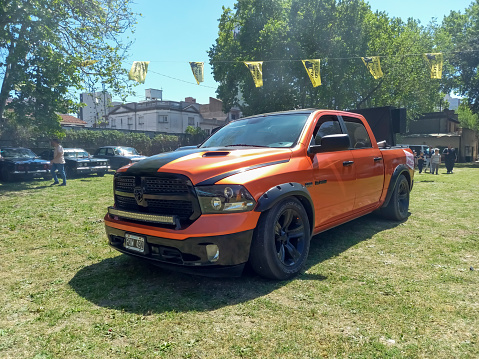Remedios de Escalada, Argentina - Oct 8, 2023: Modern orange Dodge RAM Hemi quad cab pickup truck on the lawn at a classic car show in a park. Sunny day