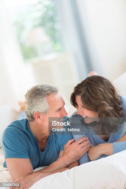 Couple Looking At Each Other While Relaxing In Bed Stock Photo - Download Image Now - 40-49 Years, 45-49 Years, Adult