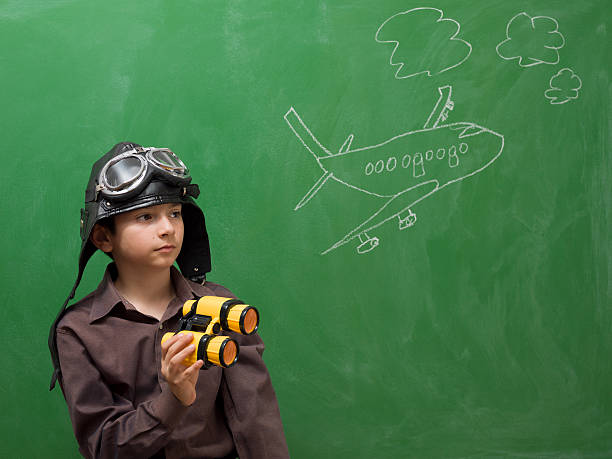 istock Little boy with flying goggles holding binoculars before blackboard 176587361
