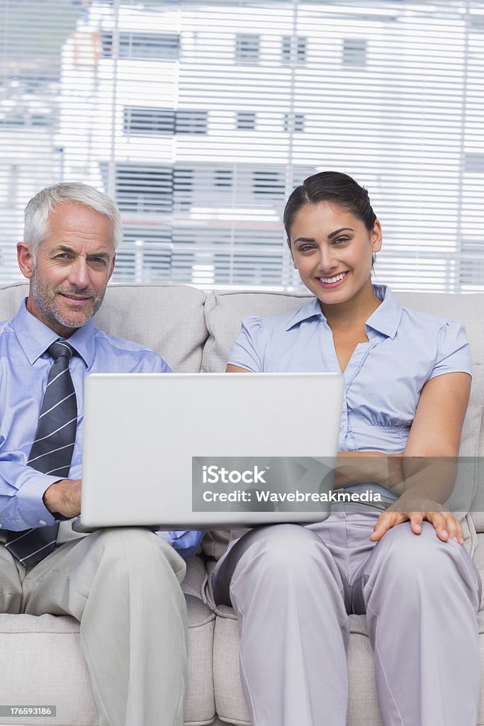 Pessoas de negócios com laptop sorrindo para câmera sentada no sofá - Foto de stock de Alta Sociedade royalty-free