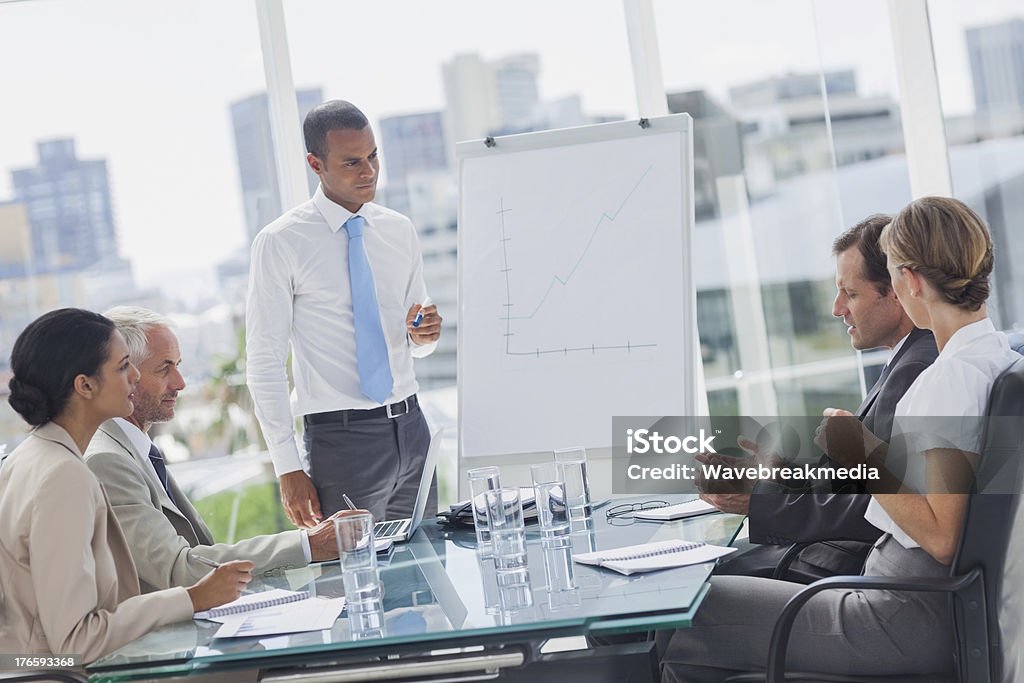 Manager standing in front of colleagues Manager standing in front of colleagues during a meeting Sales Pitch Stock Photo