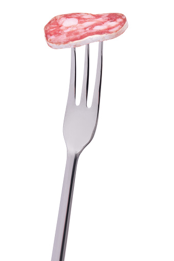 slice of Spanish Fuet thin dried salami sausage on a fork isolated on a white background