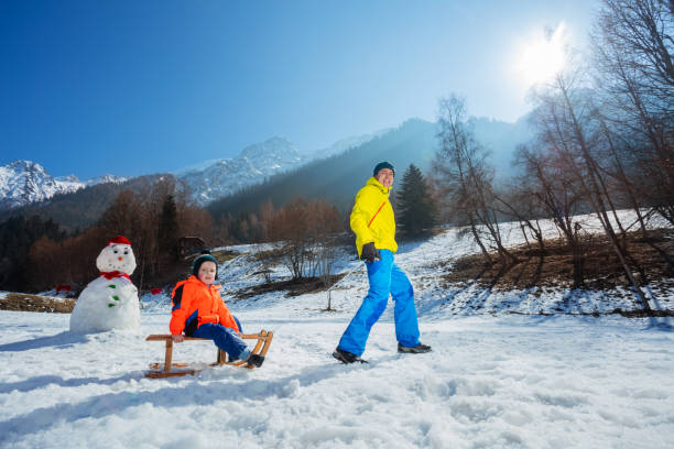 istock Father pulling uphill a boy on the wooden sledge at mountains 1765967108