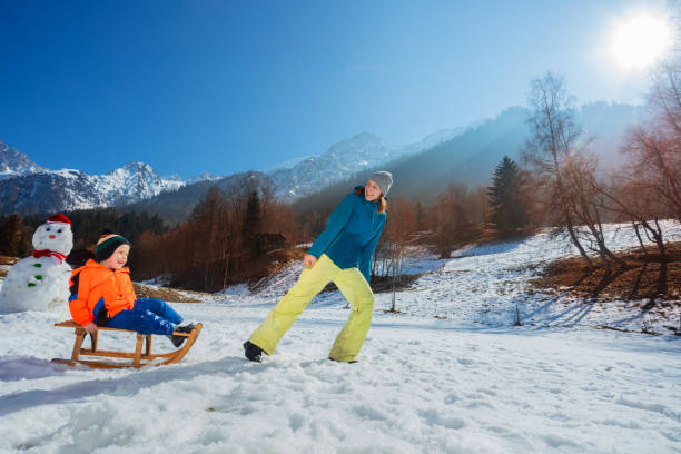 istock Mother pulling uphill a boy on the wooden sledge at mountains 1765967683
