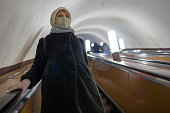 Subway transit during pandemic. In the subway station, a mature woman wearing a face mask uses the moving stairs.