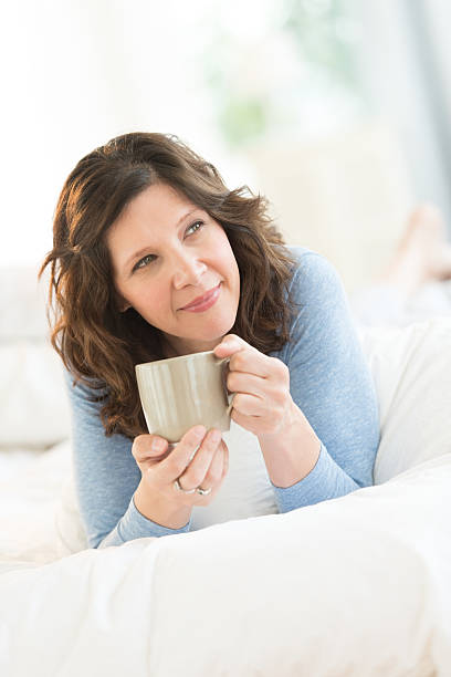 istock Thoughtful Woman Holding Coffee Mug In Bed 176601102