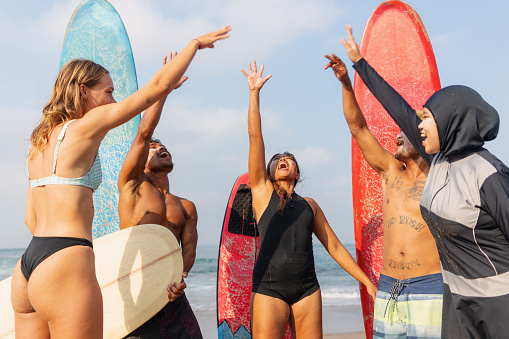 Group of Multicultural Friends Surfing in Canggu Beach Bali