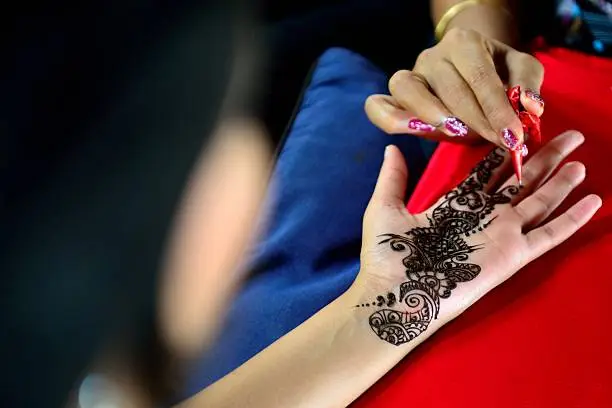 Picture of human hand being decorated with henna tattoo