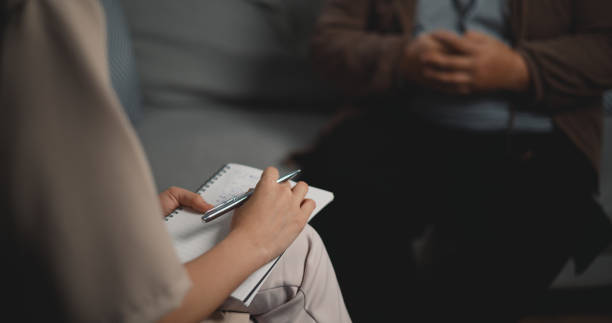 Asian therapists writing down notes during therapy with male patients