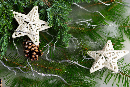 Closeup of a pine cone and snow white decorative stars on a Christmas tree. Christmas or New Year background with green fir needles, pine cones, ice sparkles and Christmas star. Winter concept, Christmas and New Year atmosphere