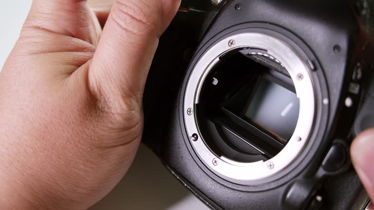 Close-up of a technician clicking the shutter and meticulously checking the sensor of a DSLR camera.