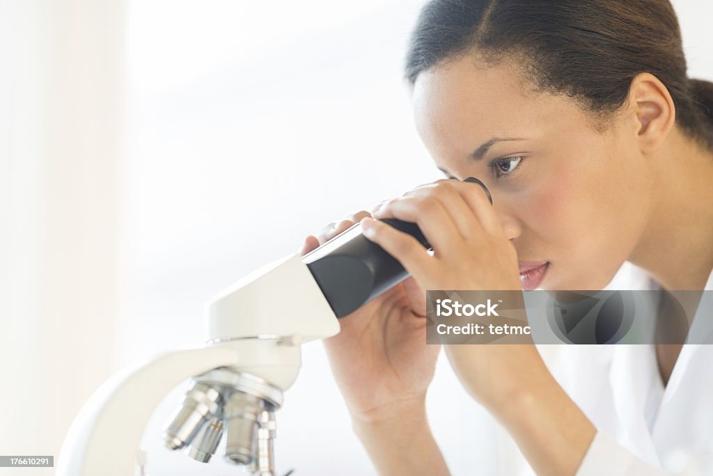 Scientist Looking a través de un microscopio en los análisis de laboratorio - Foto de stock de 25-29 años libre de derechos