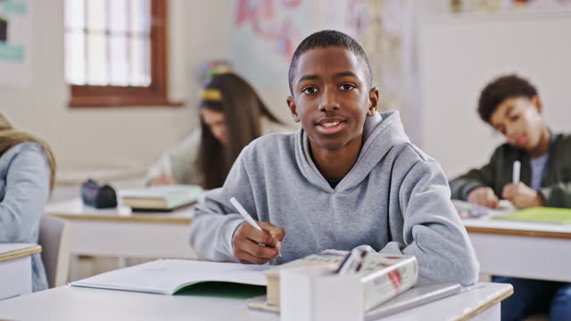 Boy, classroom and writing with student, face and learning with examination, test and knowledge. African person, academic and children with exams, education or school with paper, future and questions