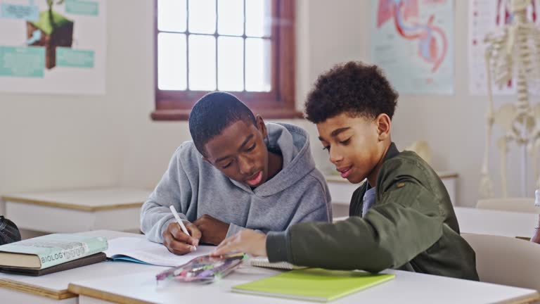 Boys, classroom and students writing, learning and conversation with support, bonding and talking. Friends, school and teamwork with knowledge, studying and education with notebook or creative