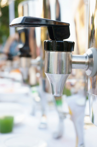 Close-up on drinks dispenser in a row at a outdoor buffet.