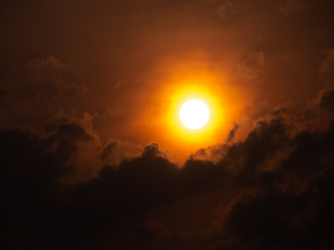 The White Sun Radiates in a Yellow Circle on a Cloudy Day in Red Background