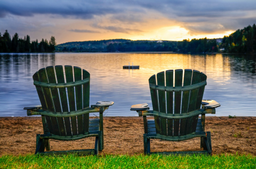 Two wooden chairs on beach of relaxing lake at sunset. Algonquin provincial park, Canada.