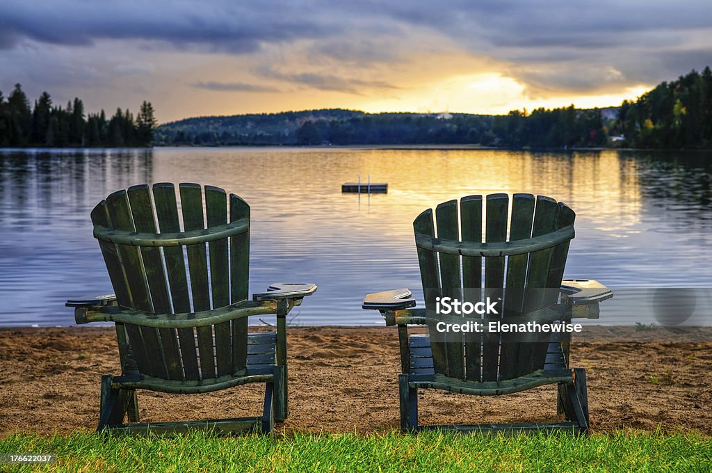 Wooden chairs at a sunset on the beach Two wooden chairs on beach of relaxing lake at sunset. Algonquin provincial park, Canada. Chair Stock Photo