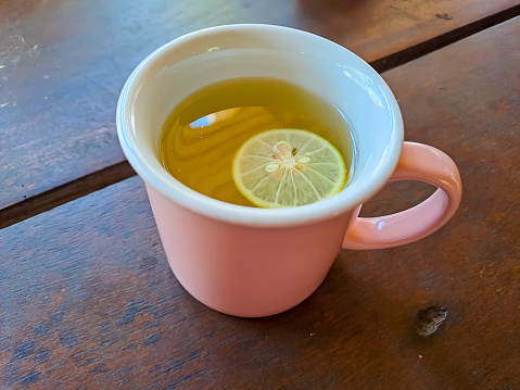 A Cup of hot tea with lemon slice on the wooden table