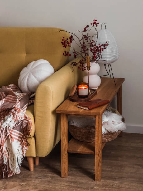 istock Cranberry branches in a ceramic vase, lit candles, notepad a paper lamp on a wooden bench next to the sofa 1766252351