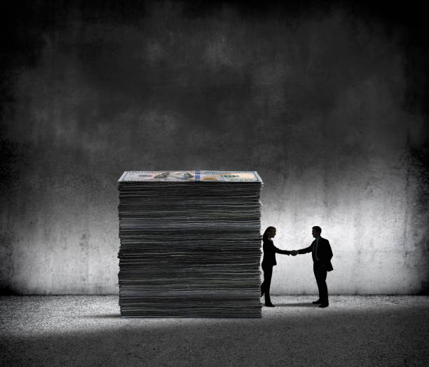 Dark Money A tall stack of money stands next to two shadowy people who are shaking hands. corruption stock pictures, royalty-free photos & images
