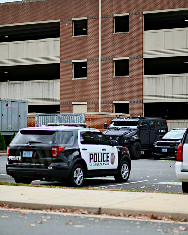 Fairfax, Virginia, USA - October 30, 2023: George Mason University Police vehicles—including a SWAT vehicle—parked adjacent to a parking garage on the University’s main campus.