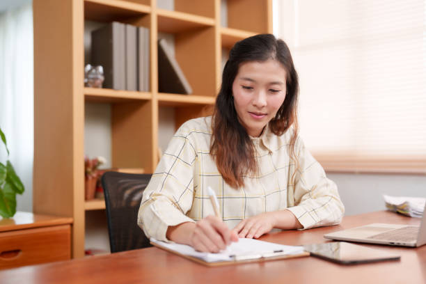 istock Asian female office worker, sitting signing documents related company work, was assigned project, before turning on laptop computer do any typing work that needs be done, with a happy face. 1766269158