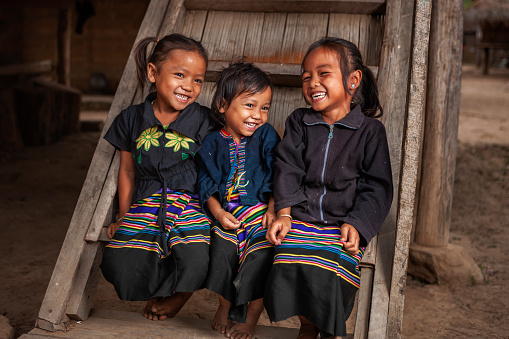 Three little girls in national dresses having fun in the village in Northern Laos.