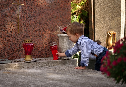 Little toddler holding a candle on the grave