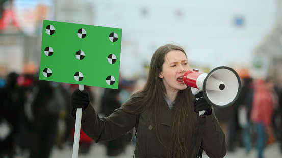 Young woman with megaphone at a demonstration in the city.