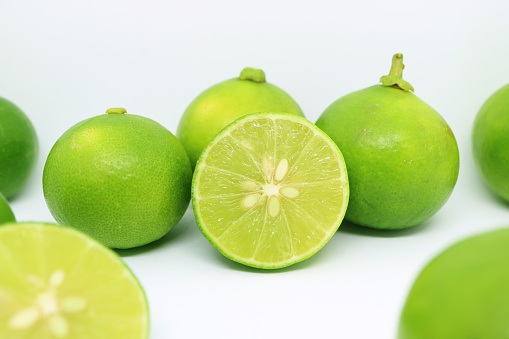 Heap of vibrant green fresh lime scattered on white background