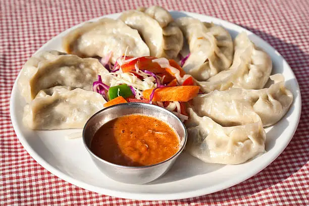 Nepalese traditional dumpling momos served with tomato chatni and fresh salad in restaurant