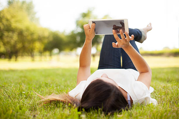 istock Woman using tablet outdoor laying on grass 176635082