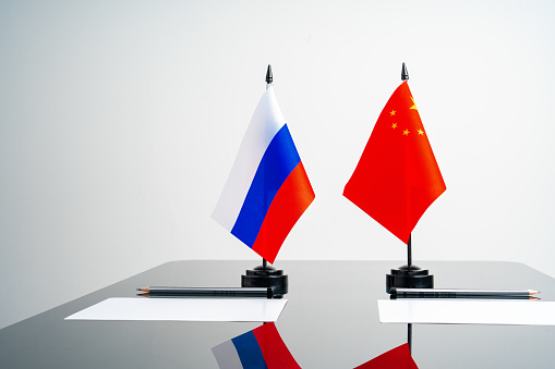 Russian and Chinese flags on negotiation table close up