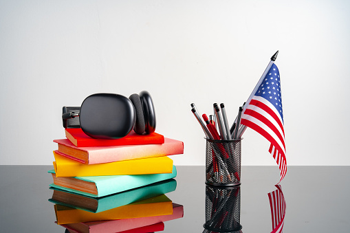 USA flag with pile of colorful books on black table close up
