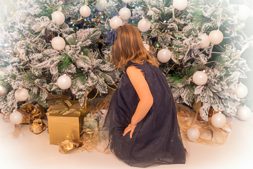 Beautiful young girl among gifts and Christmas decorations