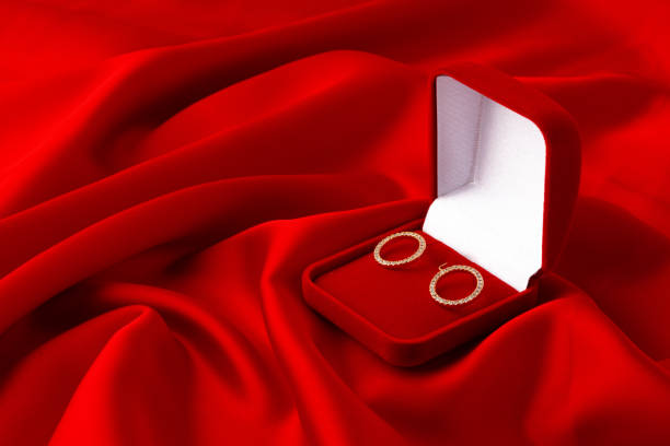 Hoop earrings in box on red silk background close up